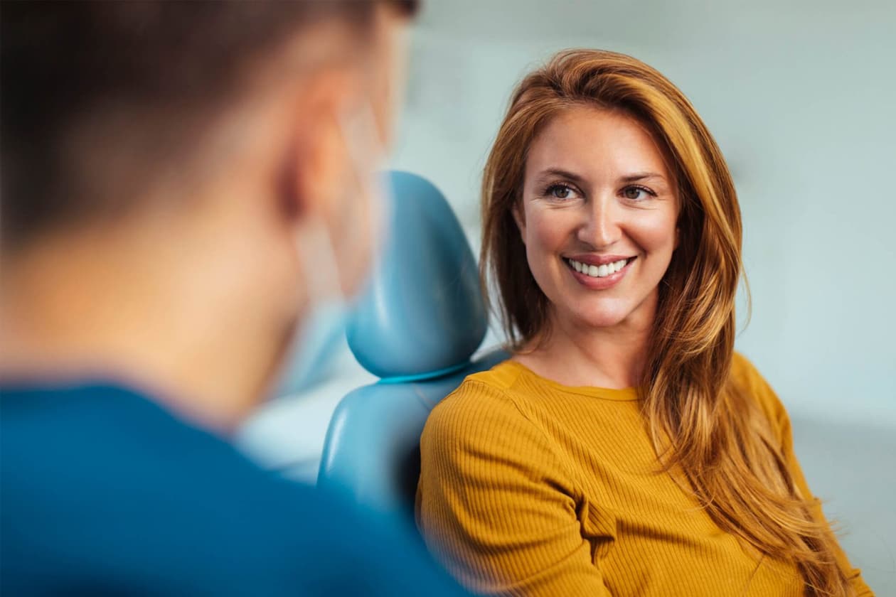 Smiling patient talking with her dentist